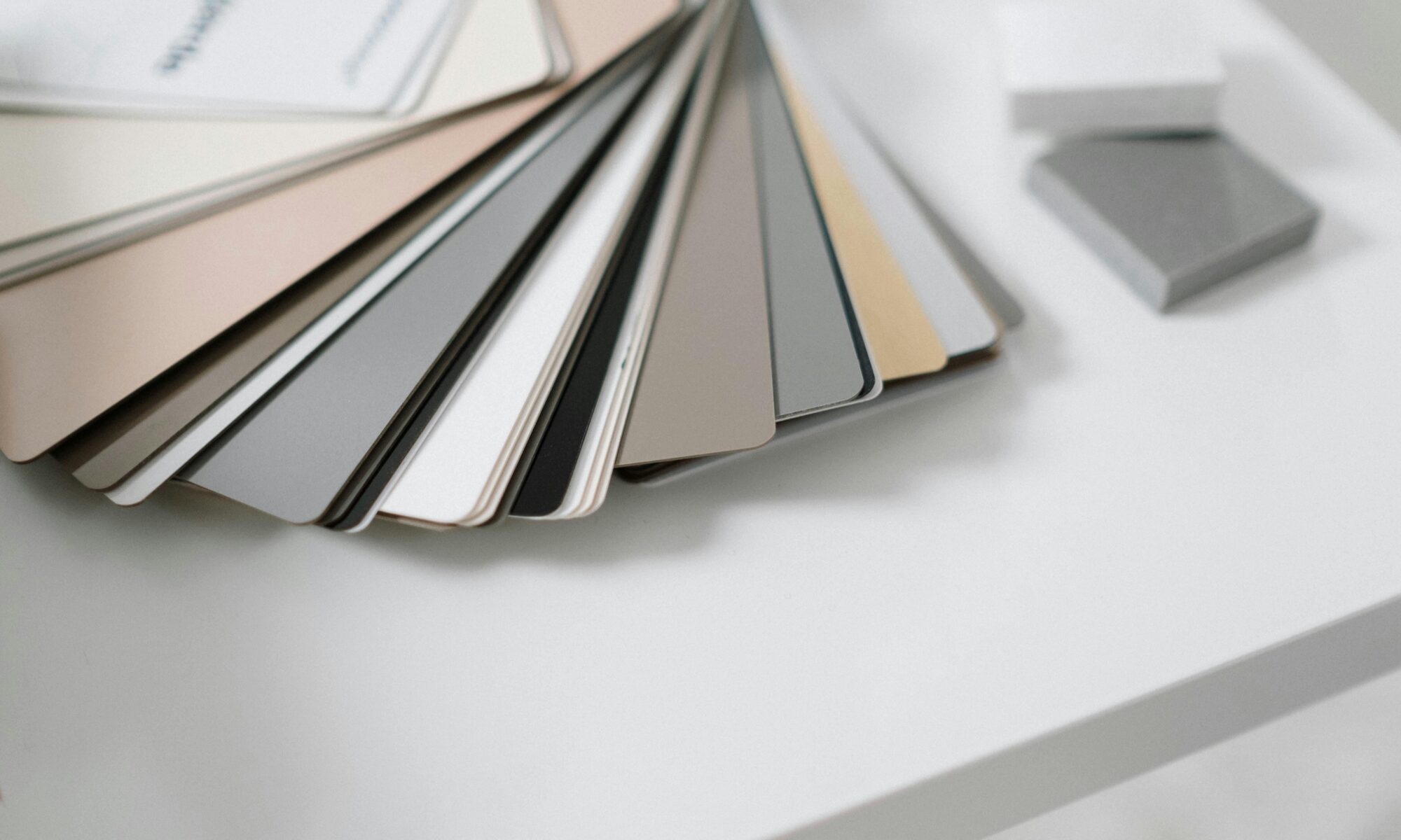 A variety of neutral color samples on a minimalist white desk for design purposes.